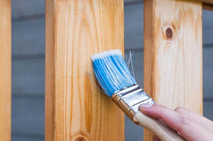 A host performing regular rental property maintenance and varnishing wood